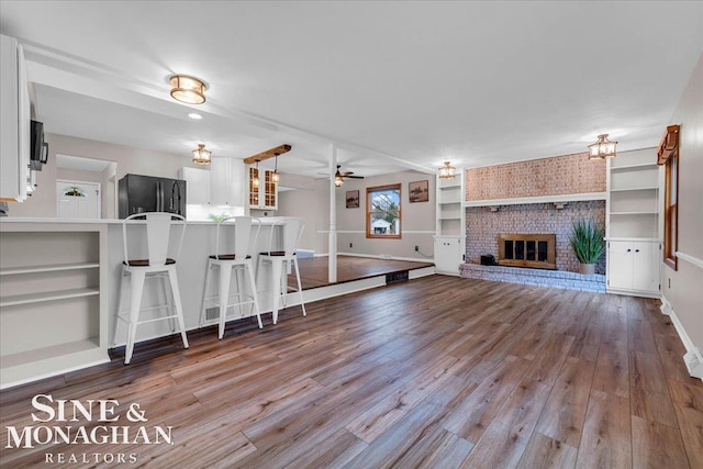 unfurnished living room featuring light hardwood / wood-style floors, a brick fireplace, and ceiling fan