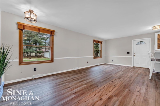 unfurnished living room with hardwood / wood-style floors and a chandelier