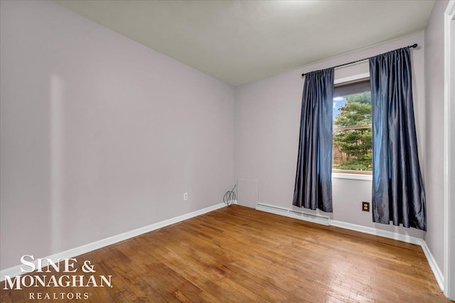 empty room featuring hardwood / wood-style floors and a baseboard radiator