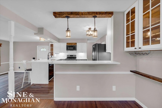 kitchen with kitchen peninsula, refrigerator, pendant lighting, stainless steel gas stove, and white cabinetry