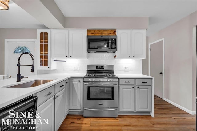 kitchen featuring decorative backsplash, white cabinetry, sink, and stainless steel appliances