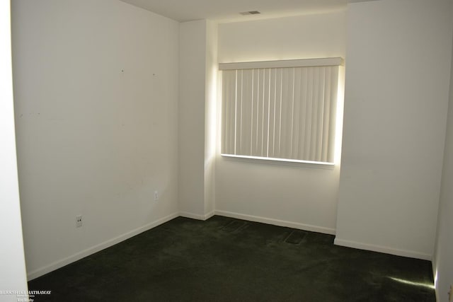 spare room with dark colored carpet