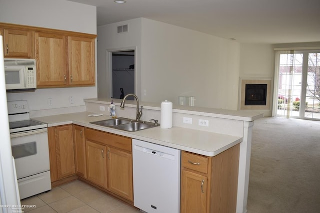 kitchen featuring sink, white appliances, light colored carpet, and kitchen peninsula