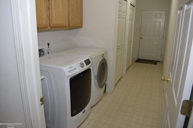 clothes washing area featuring cabinets and separate washer and dryer