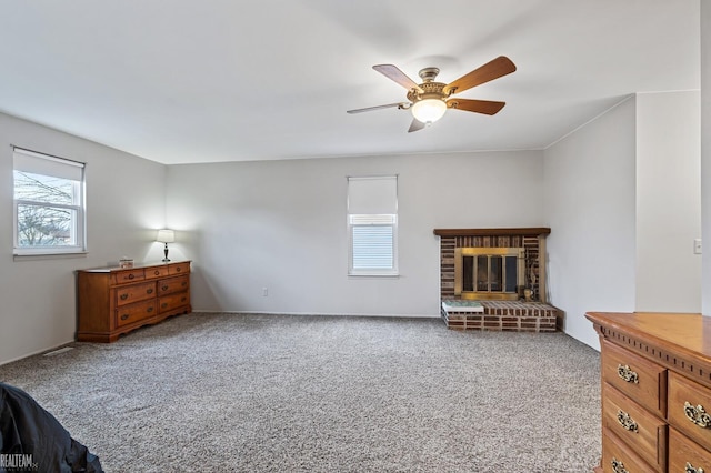 carpeted living room with ceiling fan, a fireplace, and a healthy amount of sunlight