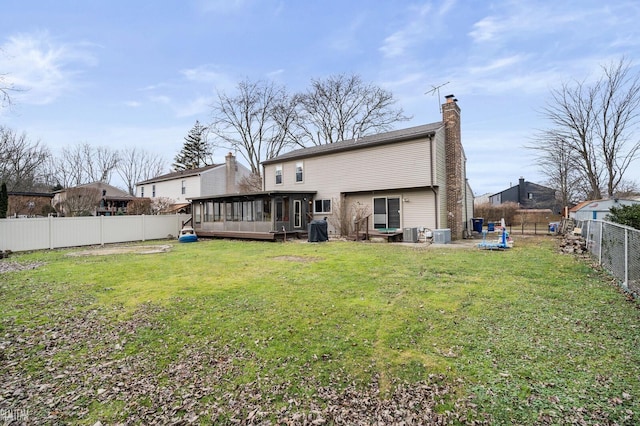 back of property featuring a sunroom, a lawn, and central AC