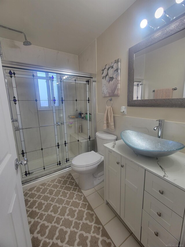 bathroom with tile patterned floors, vanity, an enclosed shower, and toilet