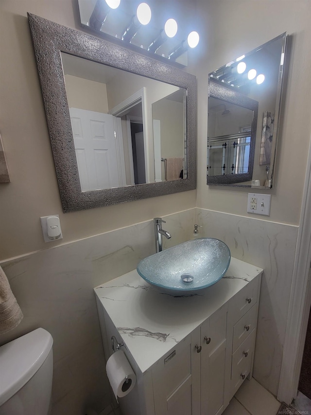 bathroom featuring vanity, toilet, and tile walls