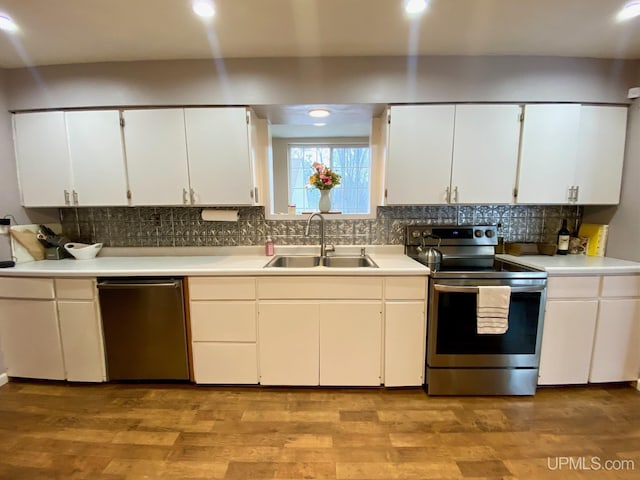 kitchen with sink, white cabinets, light wood-type flooring, and appliances with stainless steel finishes