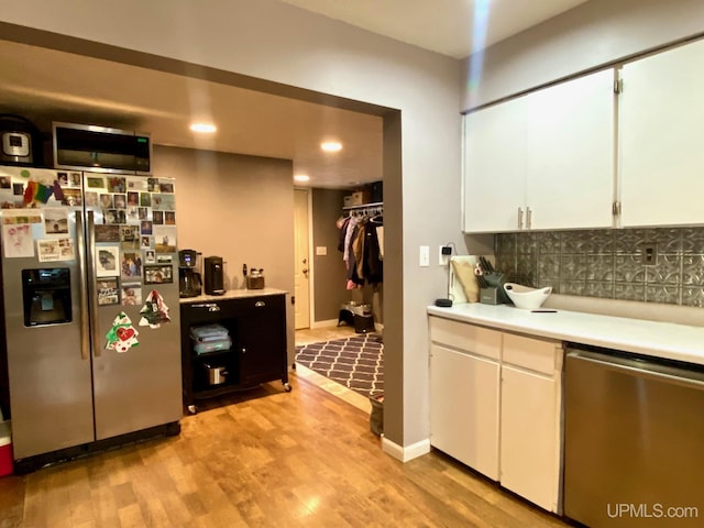 kitchen featuring tasteful backsplash, white cabinetry, stainless steel appliances, and light wood-type flooring