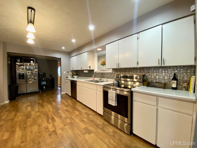 kitchen with appliances with stainless steel finishes, light wood-type flooring, sink, white cabinetry, and hanging light fixtures