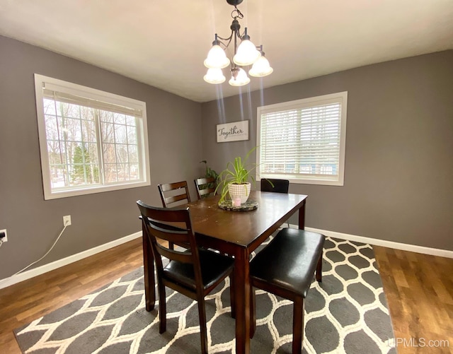 dining room with hardwood / wood-style flooring, a healthy amount of sunlight, and an inviting chandelier