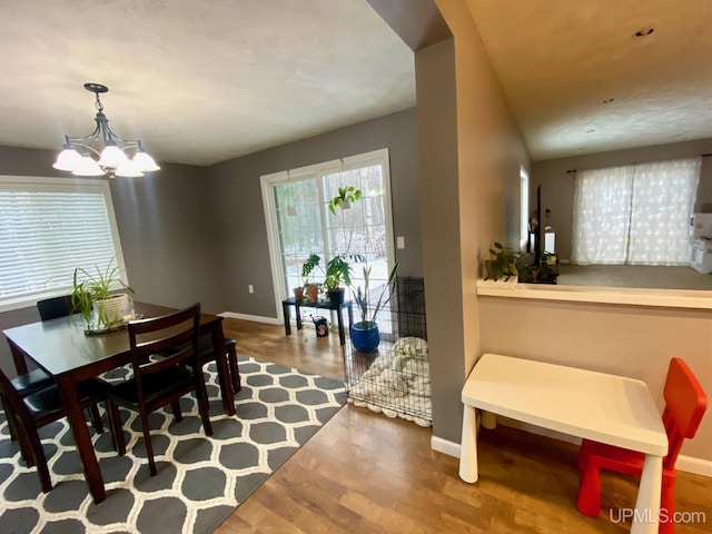 dining space featuring wood-type flooring and an inviting chandelier