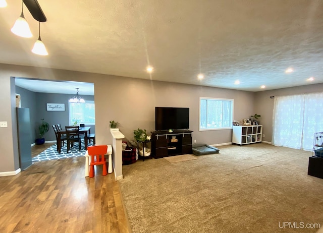 living room featuring plenty of natural light, carpet floors, a textured ceiling, and an inviting chandelier