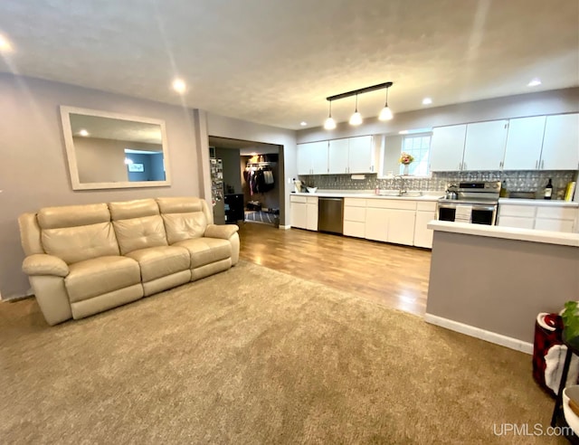 living room featuring rail lighting, sink, and light hardwood / wood-style flooring