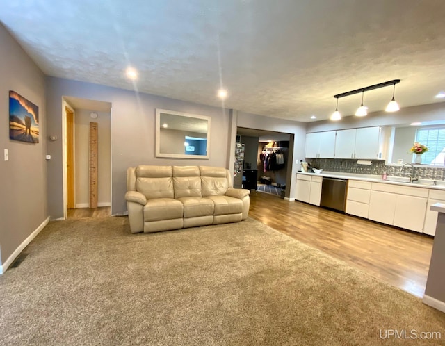 carpeted living room featuring a textured ceiling and sink