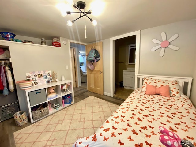 bedroom featuring connected bathroom, a closet, wood-type flooring, and an inviting chandelier