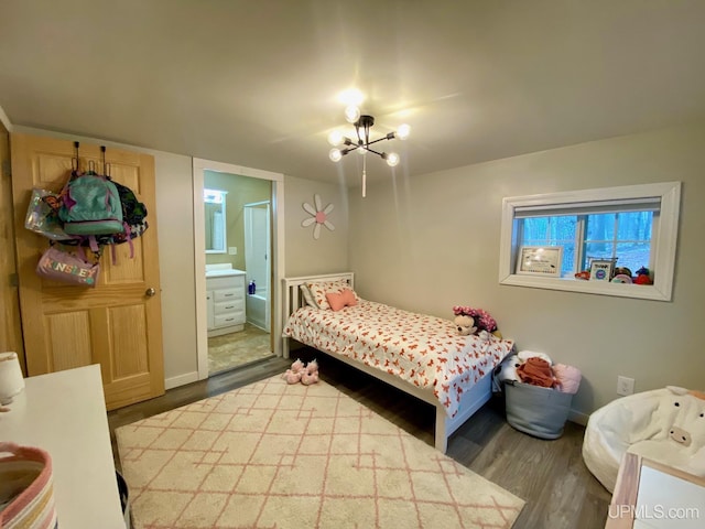 bedroom featuring connected bathroom, an inviting chandelier, and dark wood-type flooring