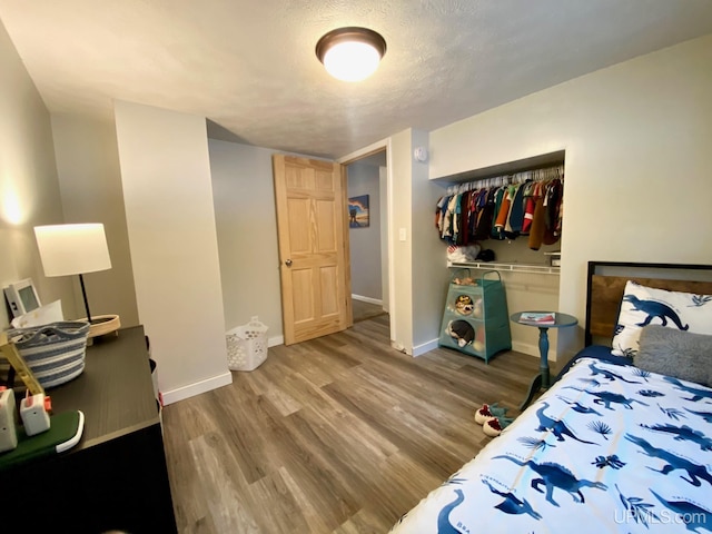 bedroom featuring wood-type flooring, a textured ceiling, and a closet