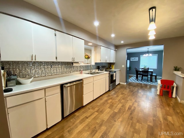 kitchen with stainless steel appliances, white cabinetry, sink, and hanging light fixtures