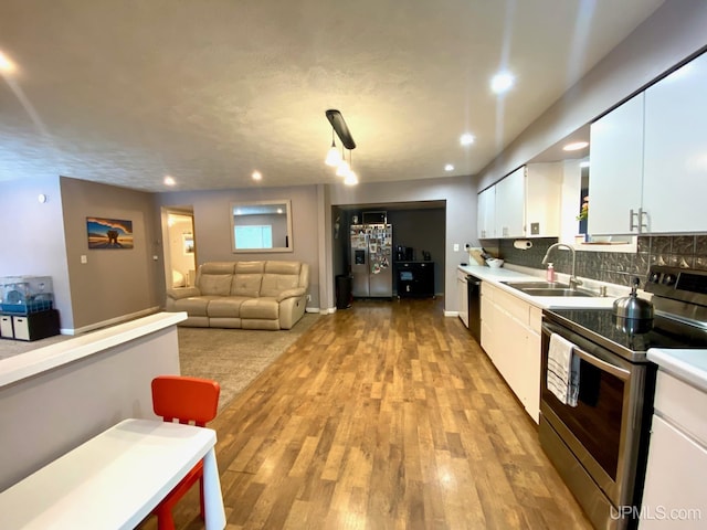 kitchen with white cabinetry, sink, tasteful backsplash, appliances with stainless steel finishes, and light wood-type flooring