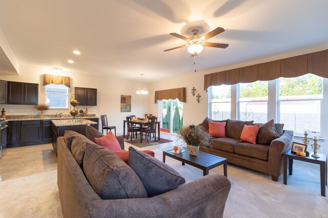 carpeted living room with sink and ceiling fan with notable chandelier