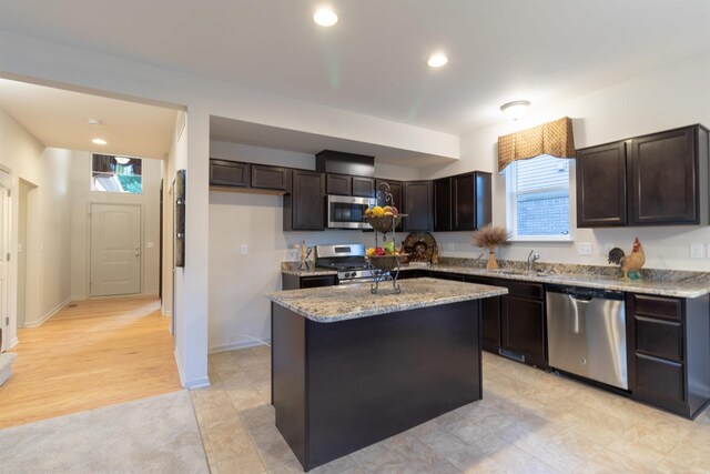 kitchen with a healthy amount of sunlight, a center island, light stone countertops, and stainless steel appliances