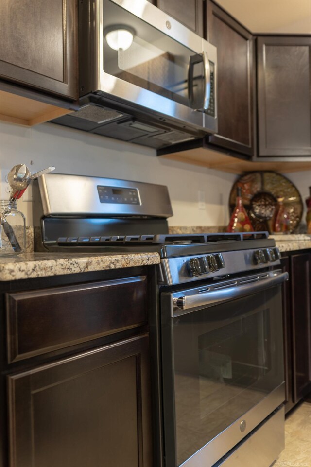 kitchen featuring light stone counters, dark brown cabinets, and stainless steel appliances