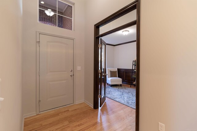 foyer entrance with light hardwood / wood-style floors and crown molding