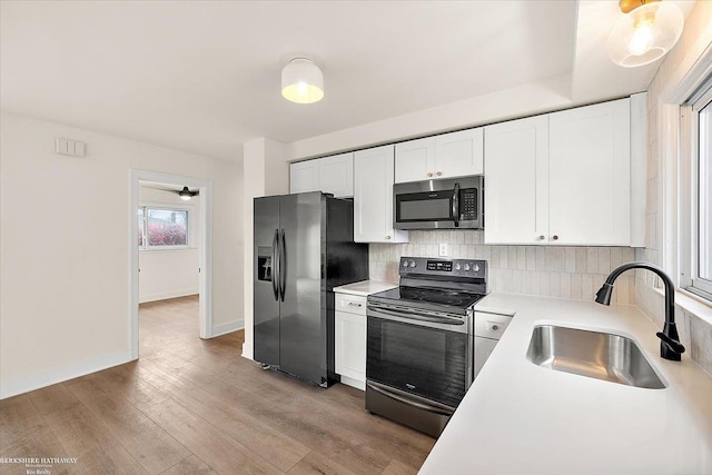 kitchen featuring backsplash, white cabinetry, sink, and appliances with stainless steel finishes