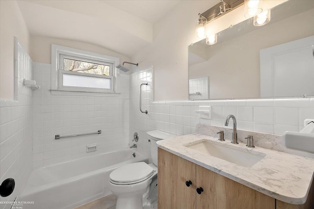 full bathroom with vanity, toilet, tile walls, and tiled shower / bath combo