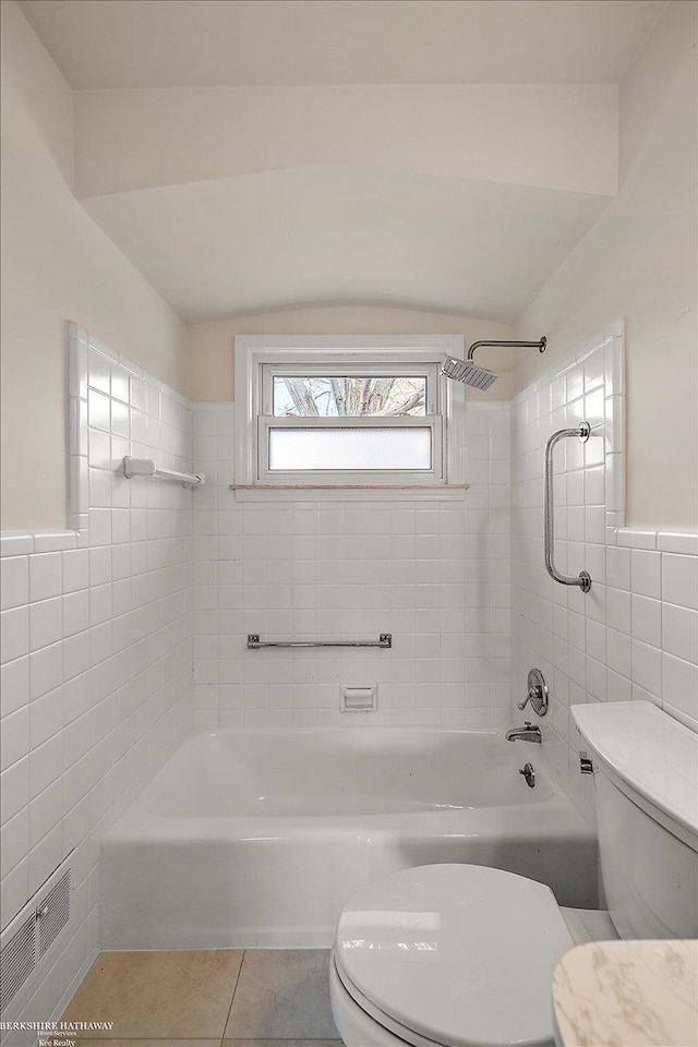 bathroom with tile patterned floors, toilet, tile walls, and tiled shower / bath