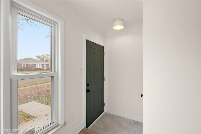 foyer entrance featuring a wealth of natural light, crown molding, and light tile patterned flooring