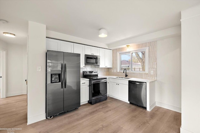 kitchen featuring appliances with stainless steel finishes, tasteful backsplash, sink, light hardwood / wood-style floors, and white cabinetry