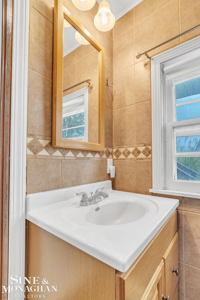 bathroom with crown molding, vanity, and tile walls