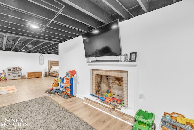 rec room featuring wood-type flooring and a brick fireplace