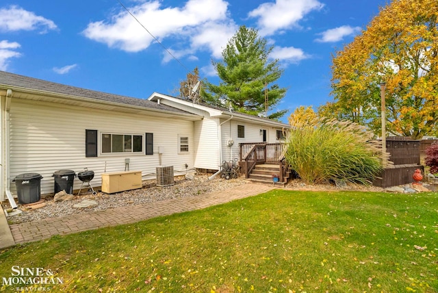 back of property with a lawn and a wooden deck