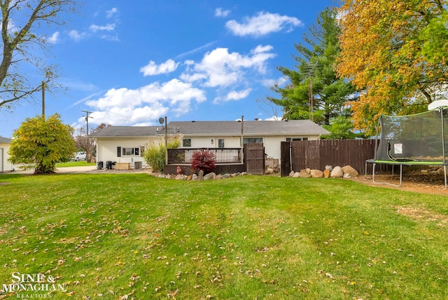 rear view of property featuring a lawn, a trampoline, and a patio