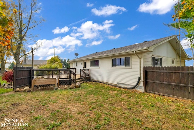 rear view of house featuring a wooden deck and a yard