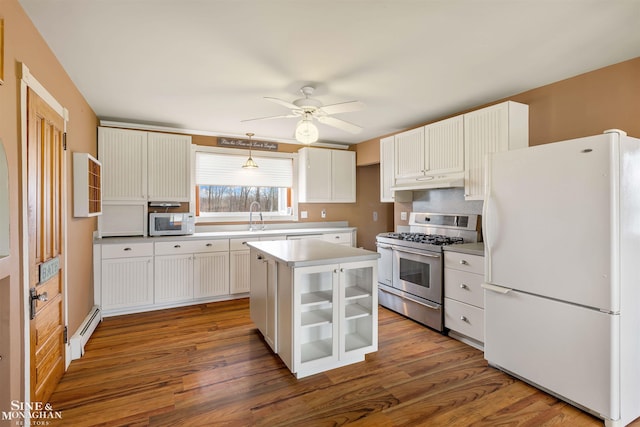 kitchen featuring white cabinetry, a center island, hanging light fixtures, a baseboard heating unit, and white appliances