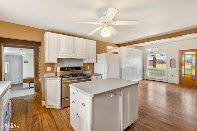 kitchen with white refrigerator, a kitchen island, white cabinetry, and stainless steel gas range