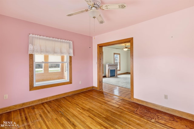 empty room with ceiling fan, hardwood / wood-style floors, and plenty of natural light