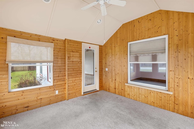 spare room with wooden walls, carpet, lofted ceiling, and ceiling fan