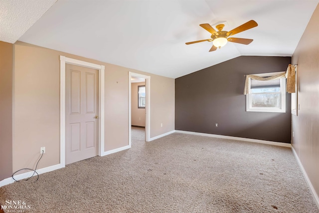 carpeted empty room featuring ceiling fan and vaulted ceiling