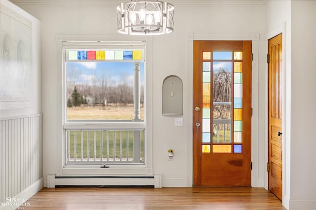 doorway featuring baseboard heating, light hardwood / wood-style flooring, and a notable chandelier