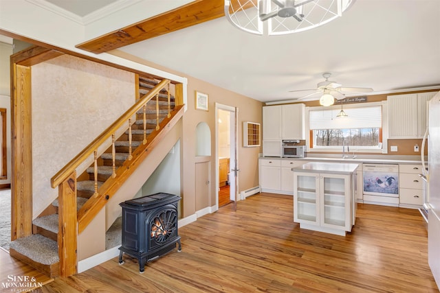 kitchen featuring white appliances, a wood stove, ceiling fan, light wood-type flooring, and white cabinetry