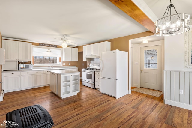 kitchen with hardwood / wood-style floors, white appliances, white cabinets, decorative light fixtures, and a kitchen island