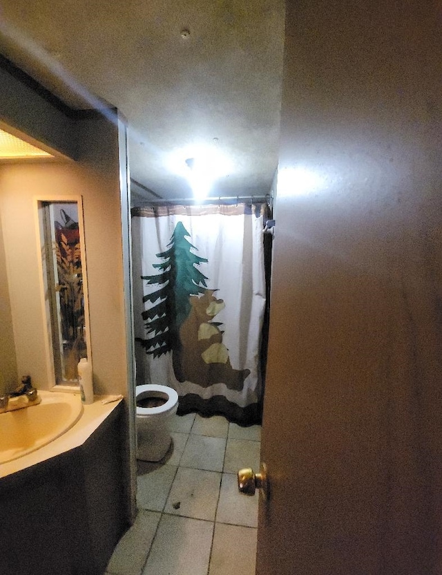 bathroom featuring tile patterned flooring, a shower with curtain, vanity, and toilet