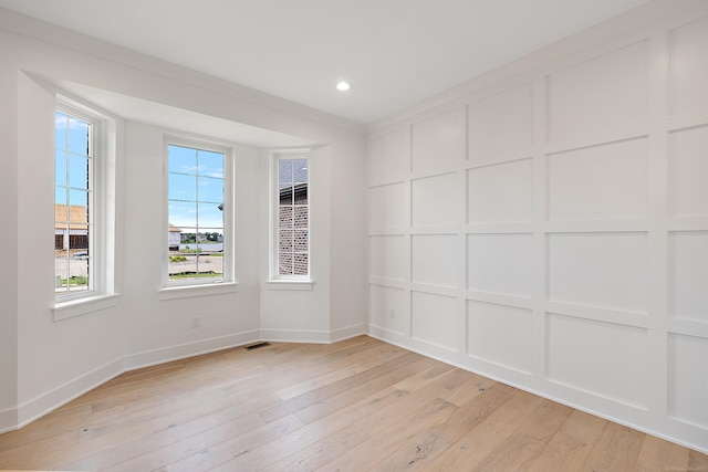 spare room featuring crown molding and light hardwood / wood-style floors