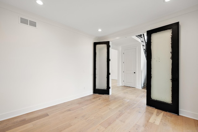 spare room featuring light wood-type flooring, french doors, and crown molding